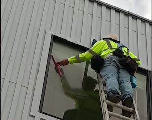 Technician on a ladder cleaning a residential window